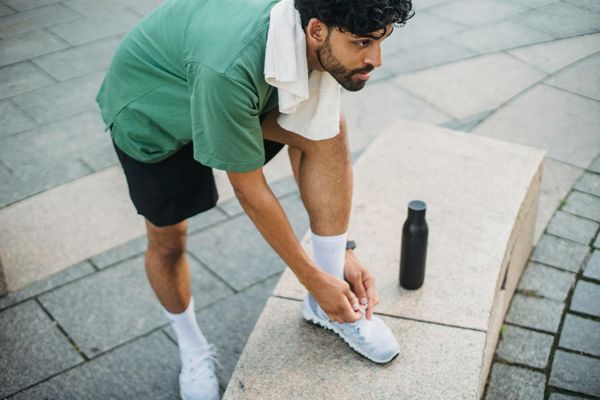 Man tying his shoelaces before a workout session.